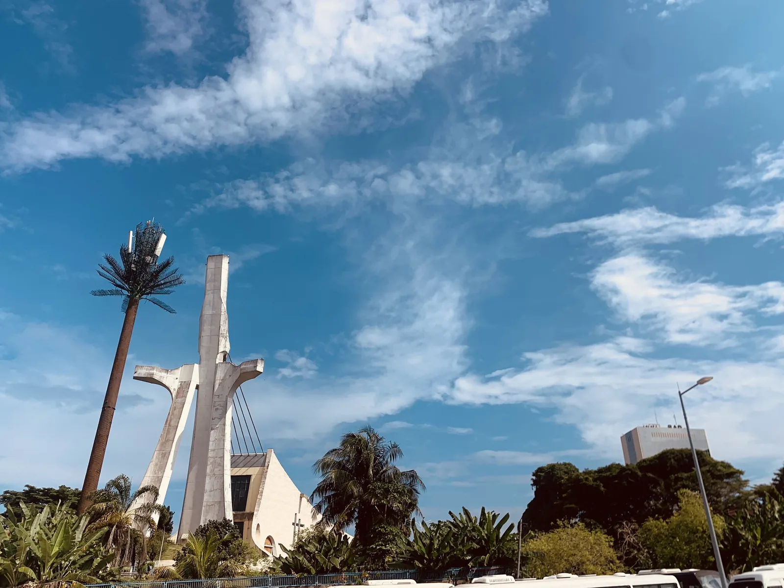 St Paul's Cathedral, Abidjan — a tall white pylon leaning over the nave with steel cables fanning down from it like a robe, above splayed concrete supports, under a blue sky