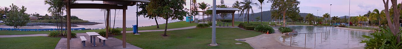 Whitehaven Beach's pristine white silica sands meeting turquoise Coral Sea waters with Whitsunday Island hills in background