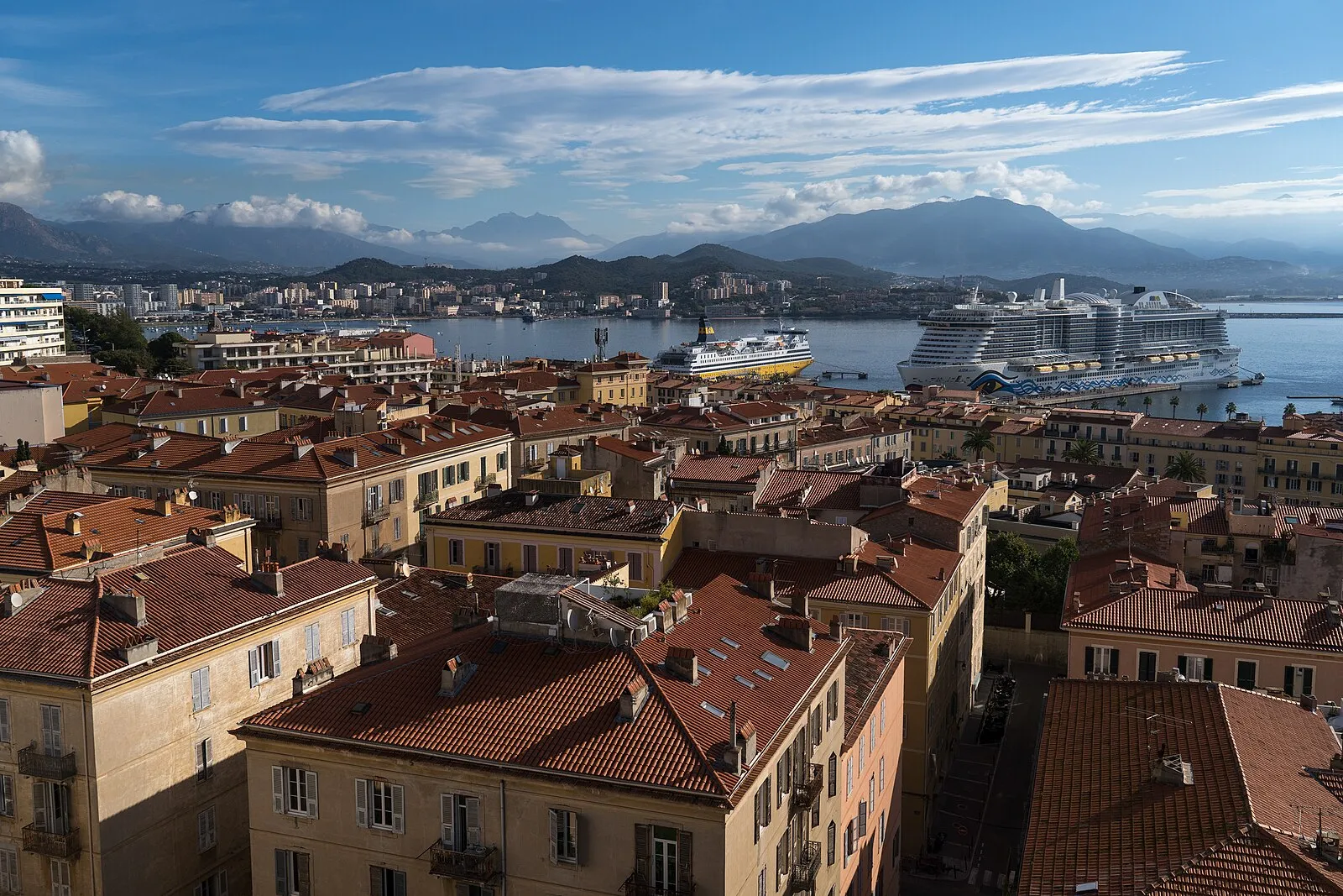 Ajaccio old town terracotta rooftops with cruise ships in harbor and Corsican mountains in background