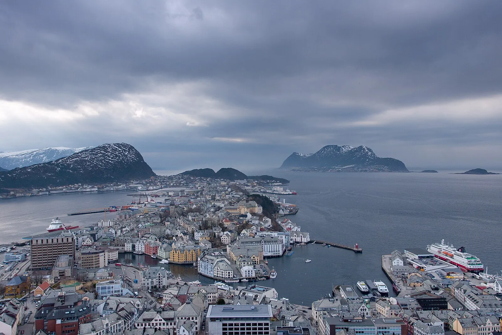 Winter view from Aksla with snowy mountains, moody clouds, and Hurtigruten ship at Ålesund pier