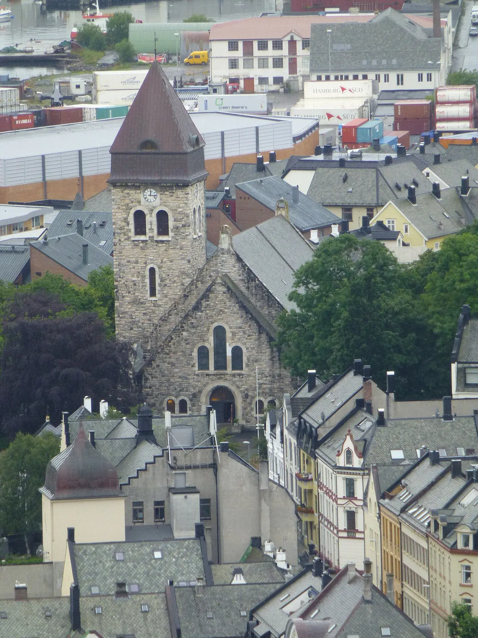Ålesund Church stone tower with clock, aerial view from Aksla with harbor containers behind