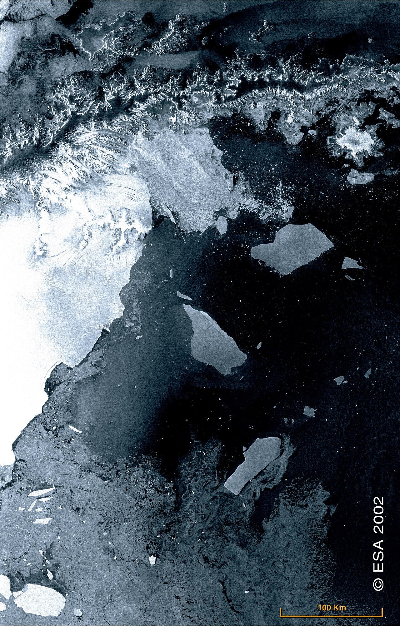 Massive glacier face with ice calving into dark Antarctic waters creating splash and waves