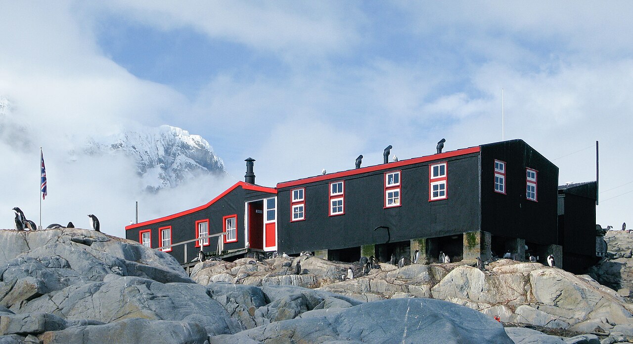 Historic British base Port Lockroy with red building surrounded by penguins and snow