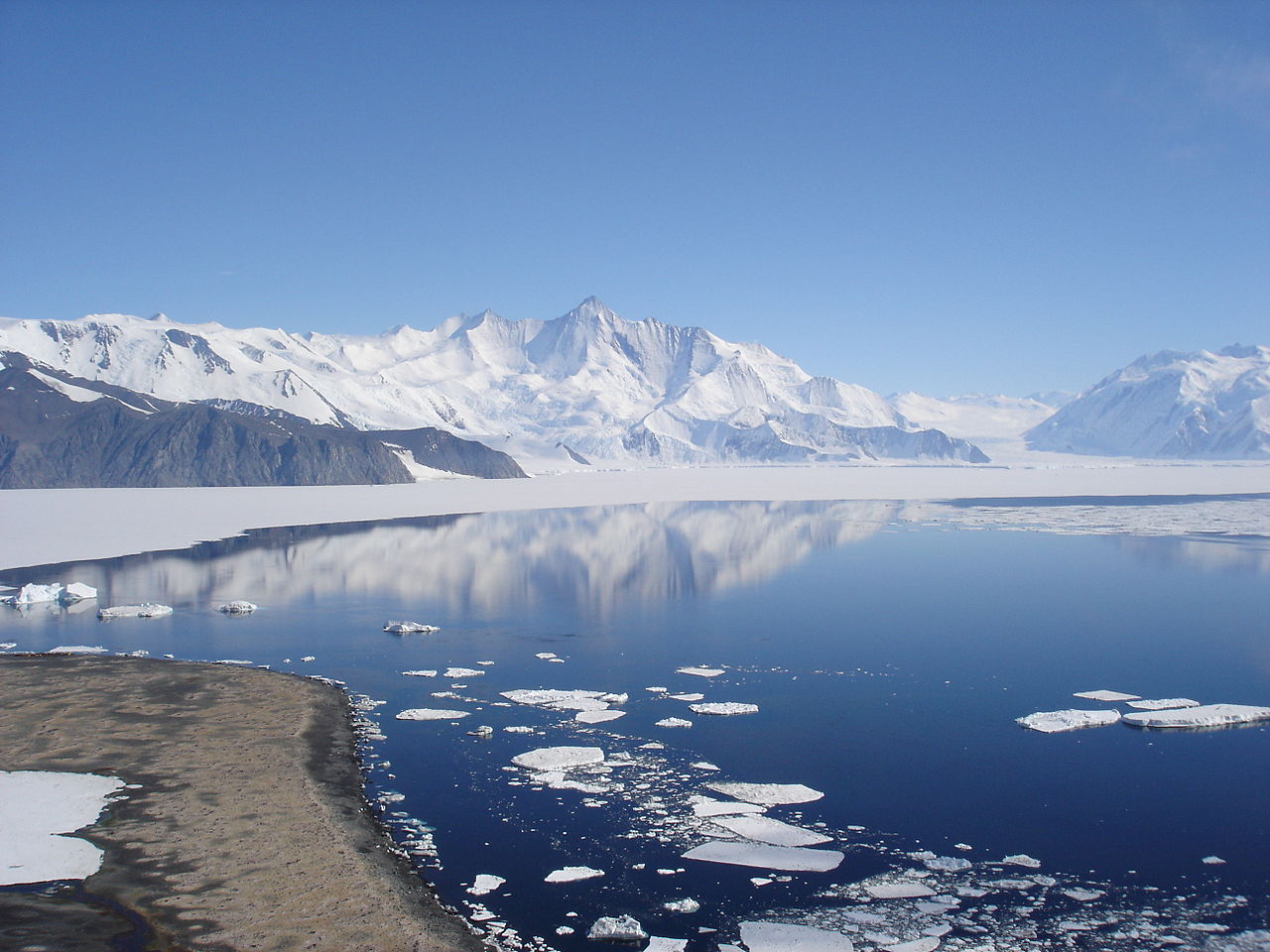 Antarctic mountain landscape with reflective water and ice floes