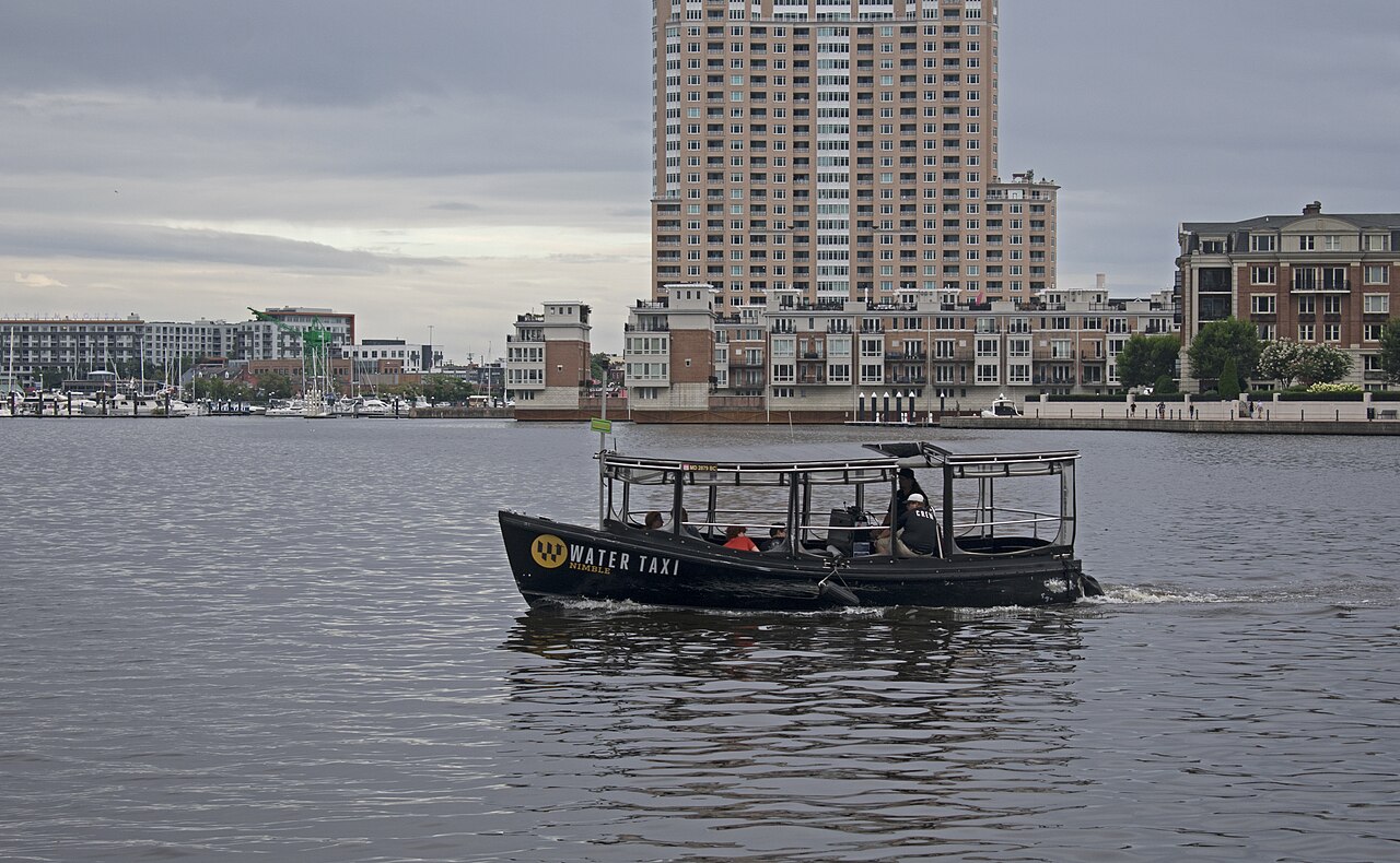 Baltimore Water Taxi boat crossing Inner Harbor with city skyline behind