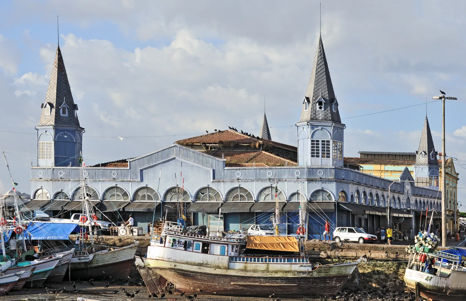 The Ver-o-Peso market hall at Belém with its blue ironwork and corner turrets, seen across the fishing basin with boats moored in front