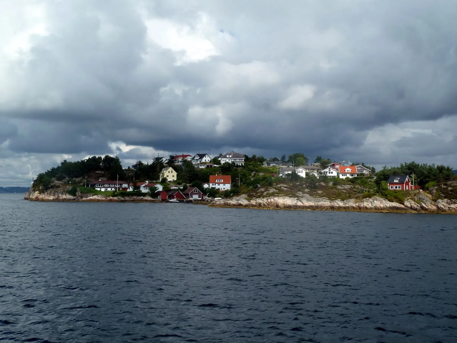 Wet cobblestone street in Bergen with colorful umbrellas and wooden buildings