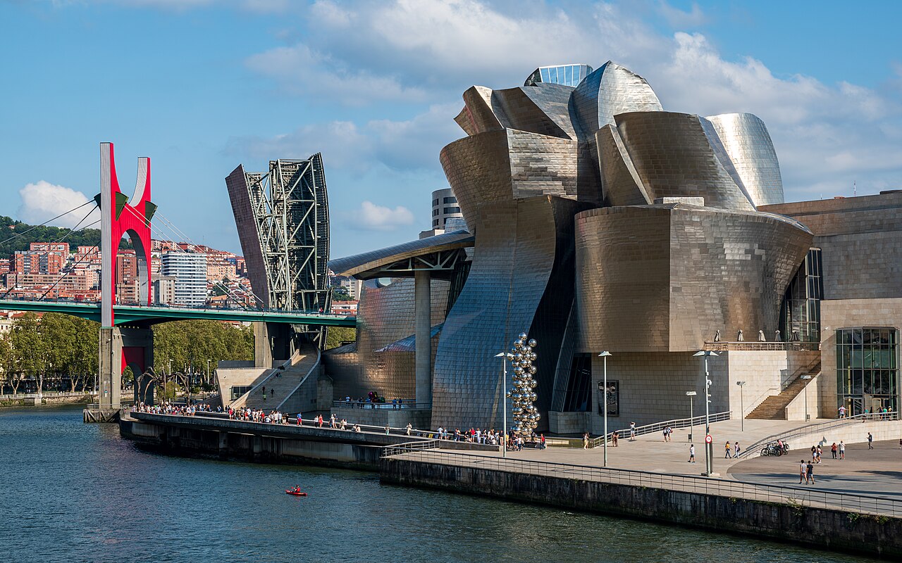 Bilbao Guggenheim Museum with titanium curves reflecting on the Nervión River at sunset