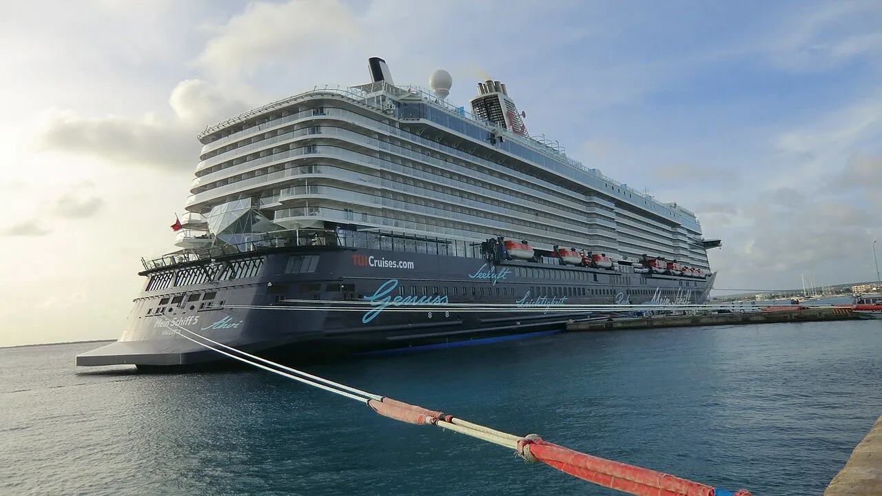 Mein Schiff 5 cruise ship docked at Kralendijk pier with the island's colorful buildings behind
