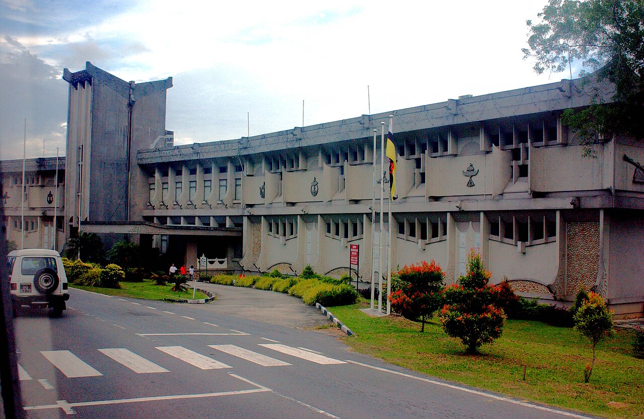 Brunei government building with national emblems on facade and Brunei flag flying