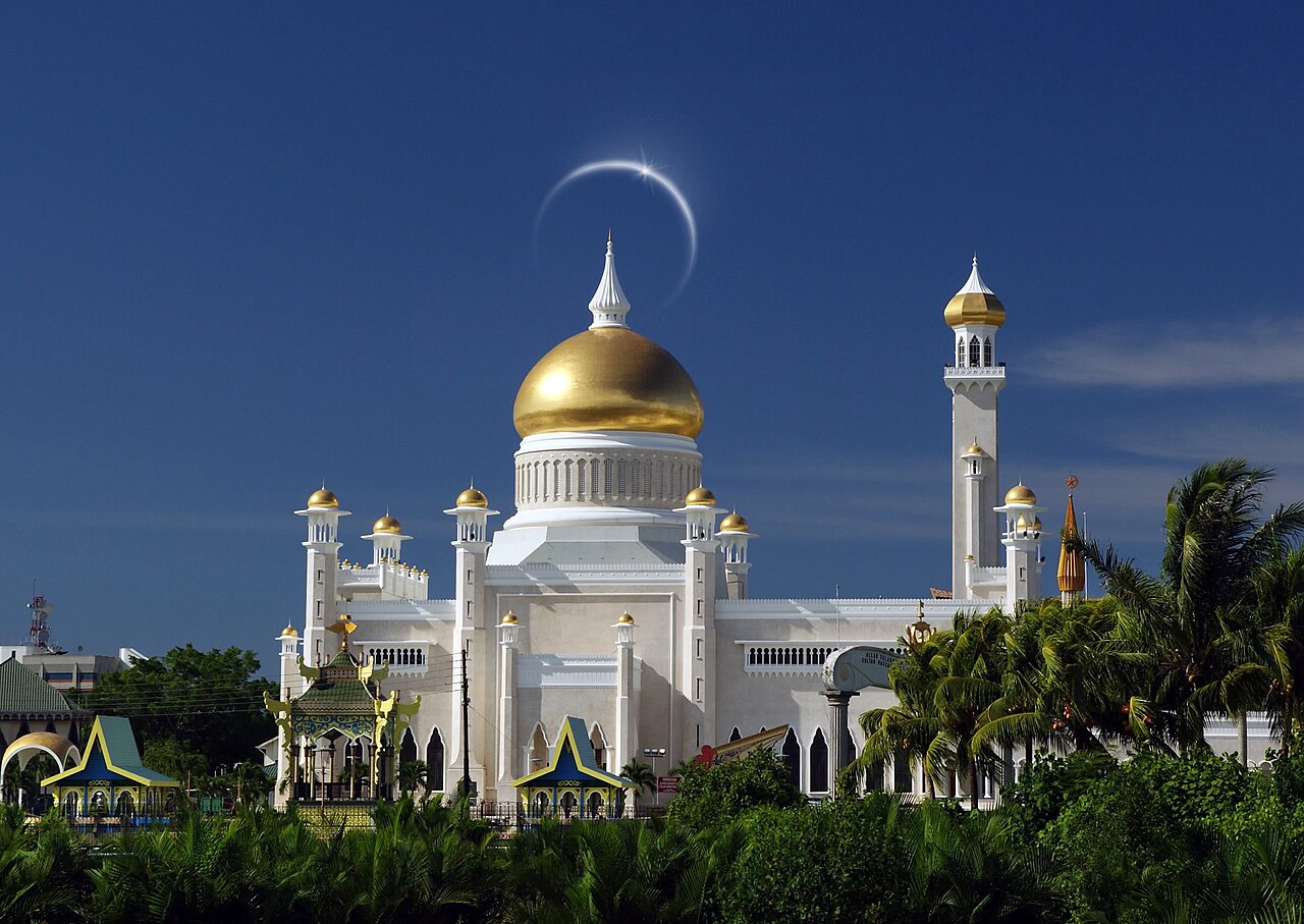 Omar Ali Saifuddien Mosque with golden dome and white marble walls, with a solar eclipse ring visible behind the dome