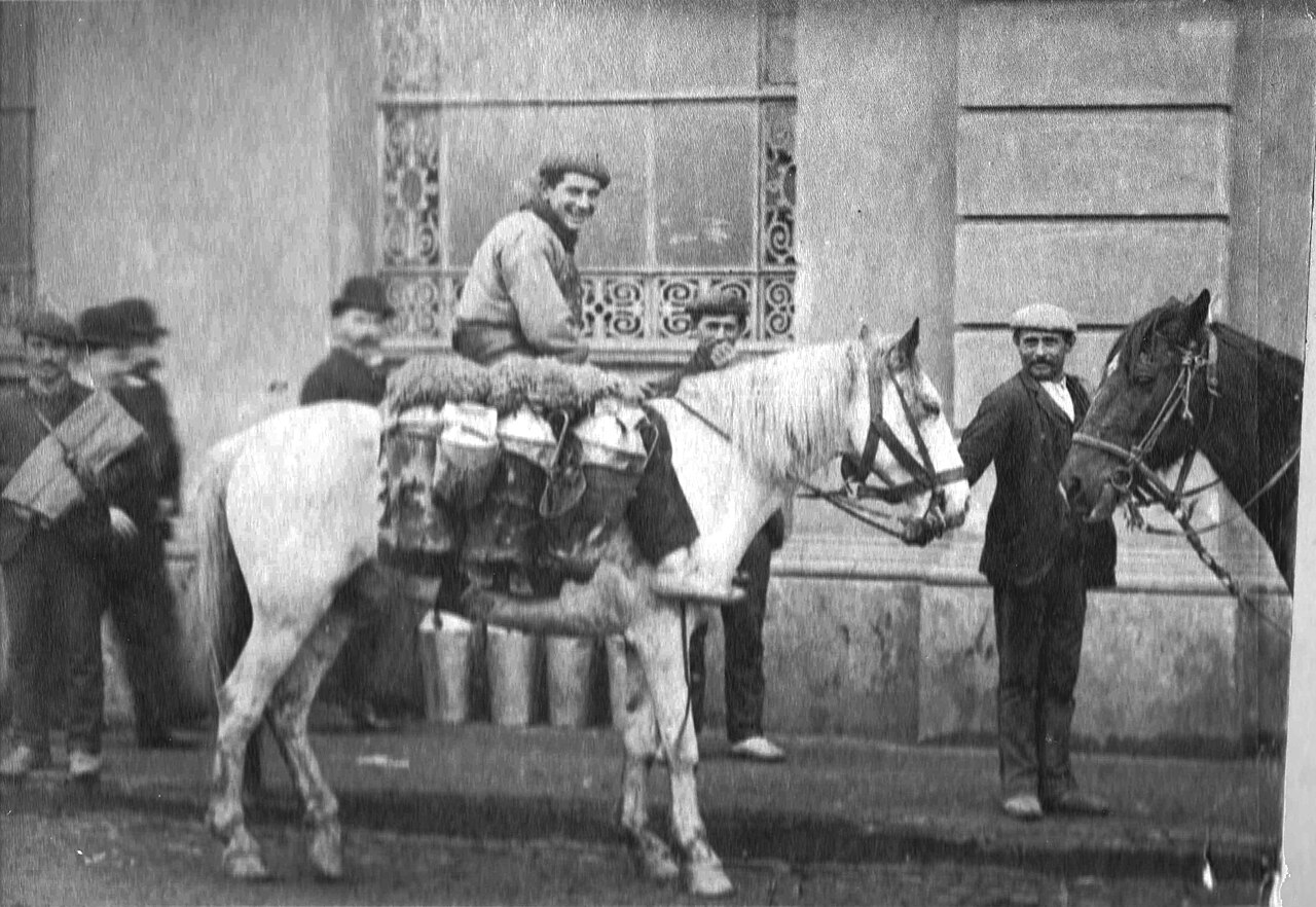 Historical black and white photograph of a young delivery boy on horseback in front of an Art Nouveau building in Buenos Aires