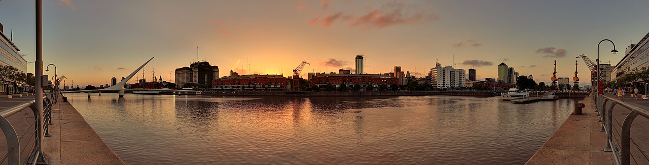 Puerto Madero sunset panorama with Puente de la Mujer bridge, converted warehouses, and Buenos Aires skyline reflected in the dock basin