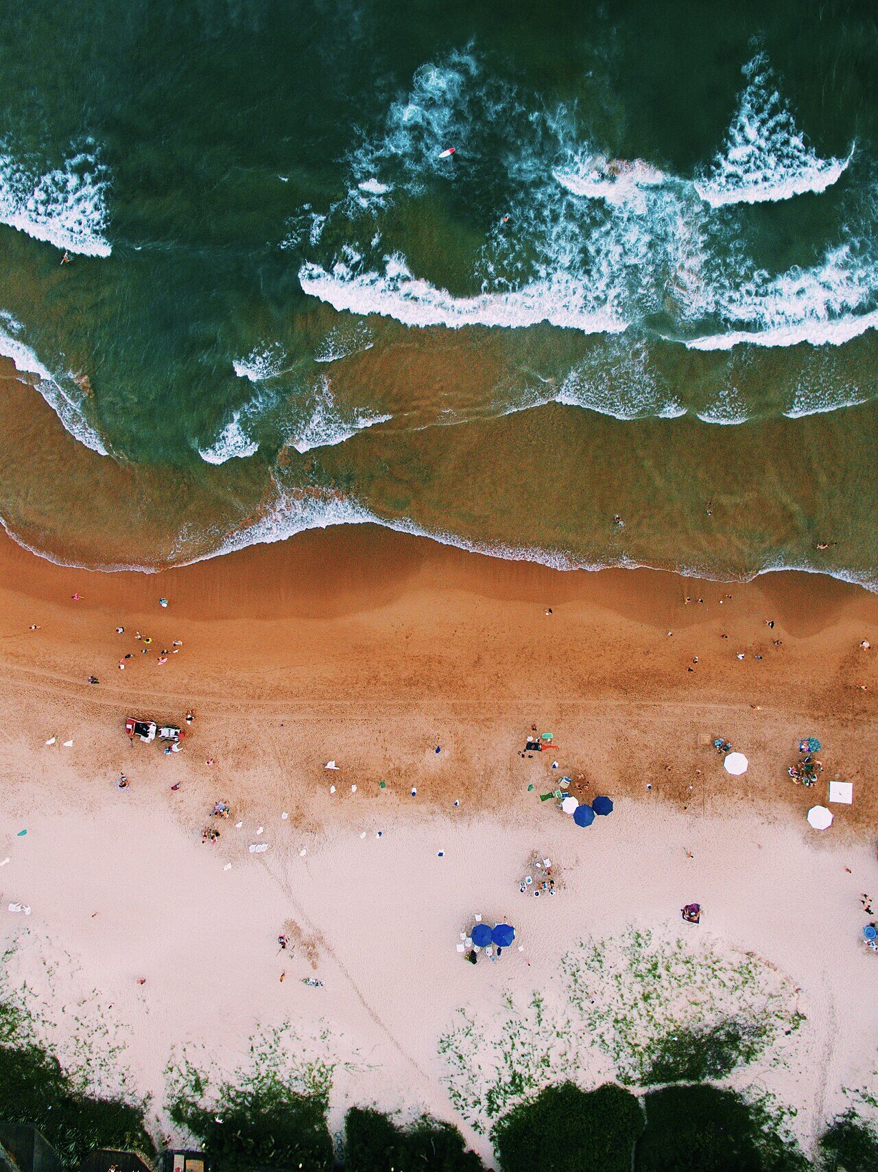 Aerial drone view of Brazilian beach with green waves and beachgoers