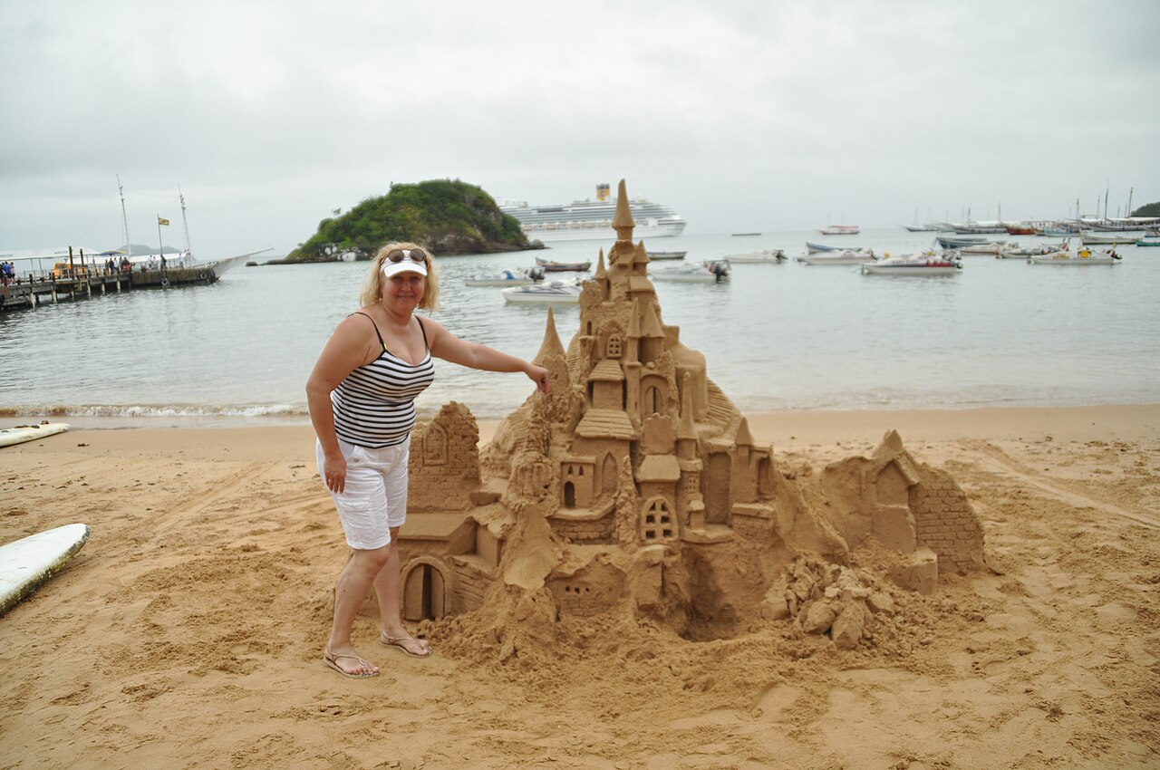 Sand castle on Búzios beach with cruise ship anchored in bay behind