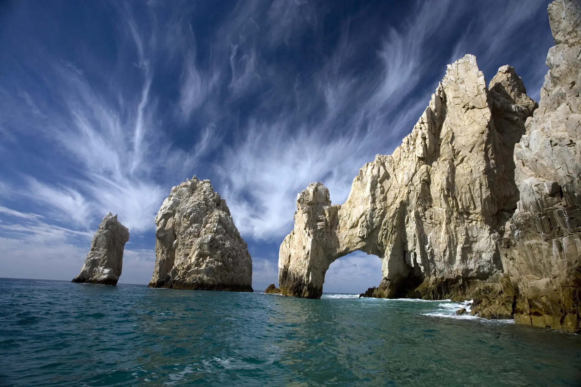 Dramatic desert cliffs of Cabo San Lucas plunging into turquoise waters where the Pacific Ocean meets the Sea of Cortez