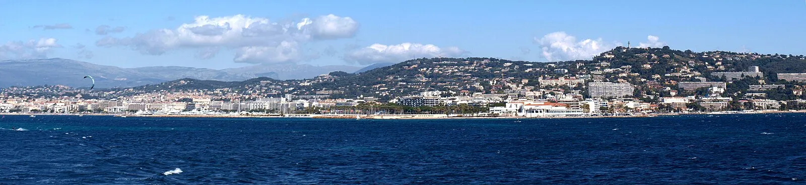 Narrow cobblestone street in Le Suquet with ochre buildings and green shutters