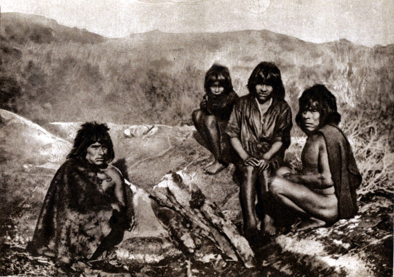 Historical sepia photograph of four Yaghan indigenous people of Tierra del Fuego wearing fur pelts