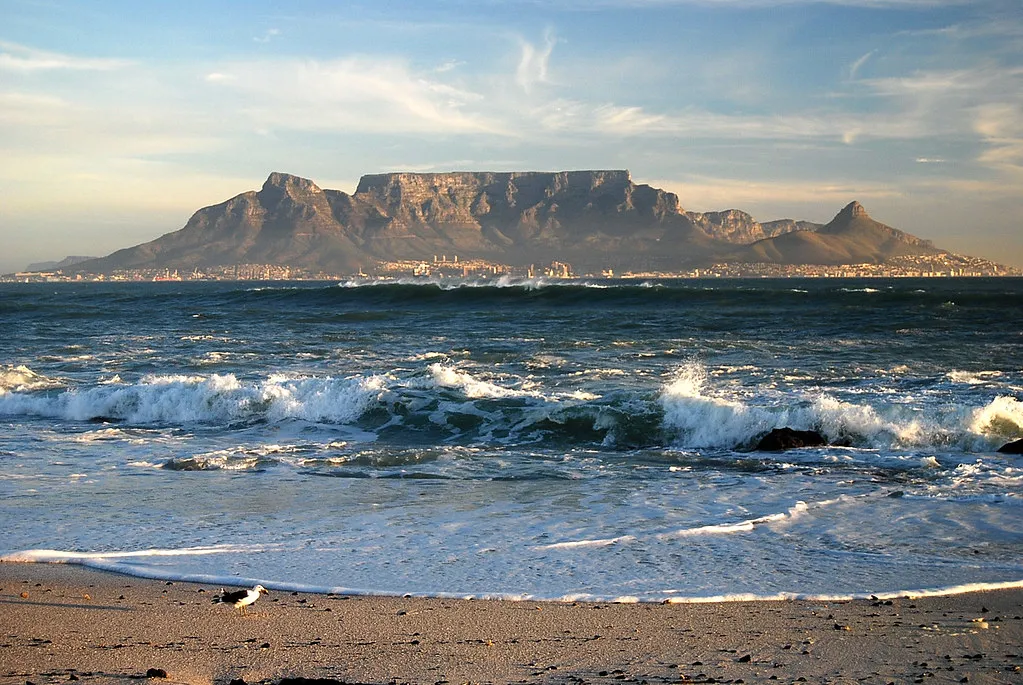 Table Mountain rising above Cape Town seen from across Table Bay with ocean waves in the foreground