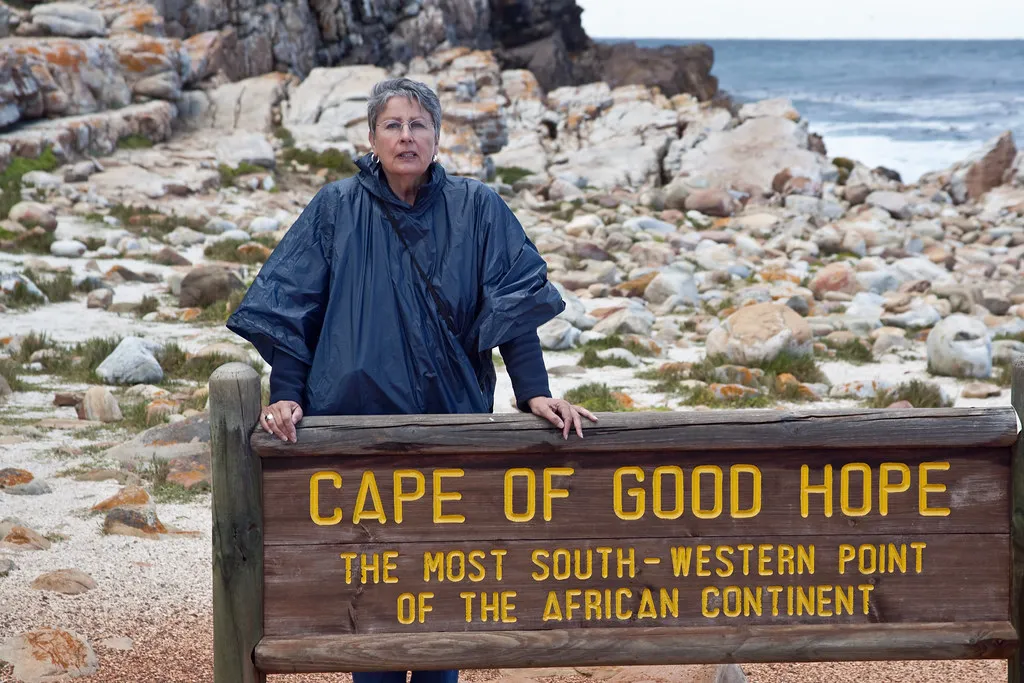 Visitor at the Cape of Good Hope signpost marking the most south-western point of Africa with rocky coastline