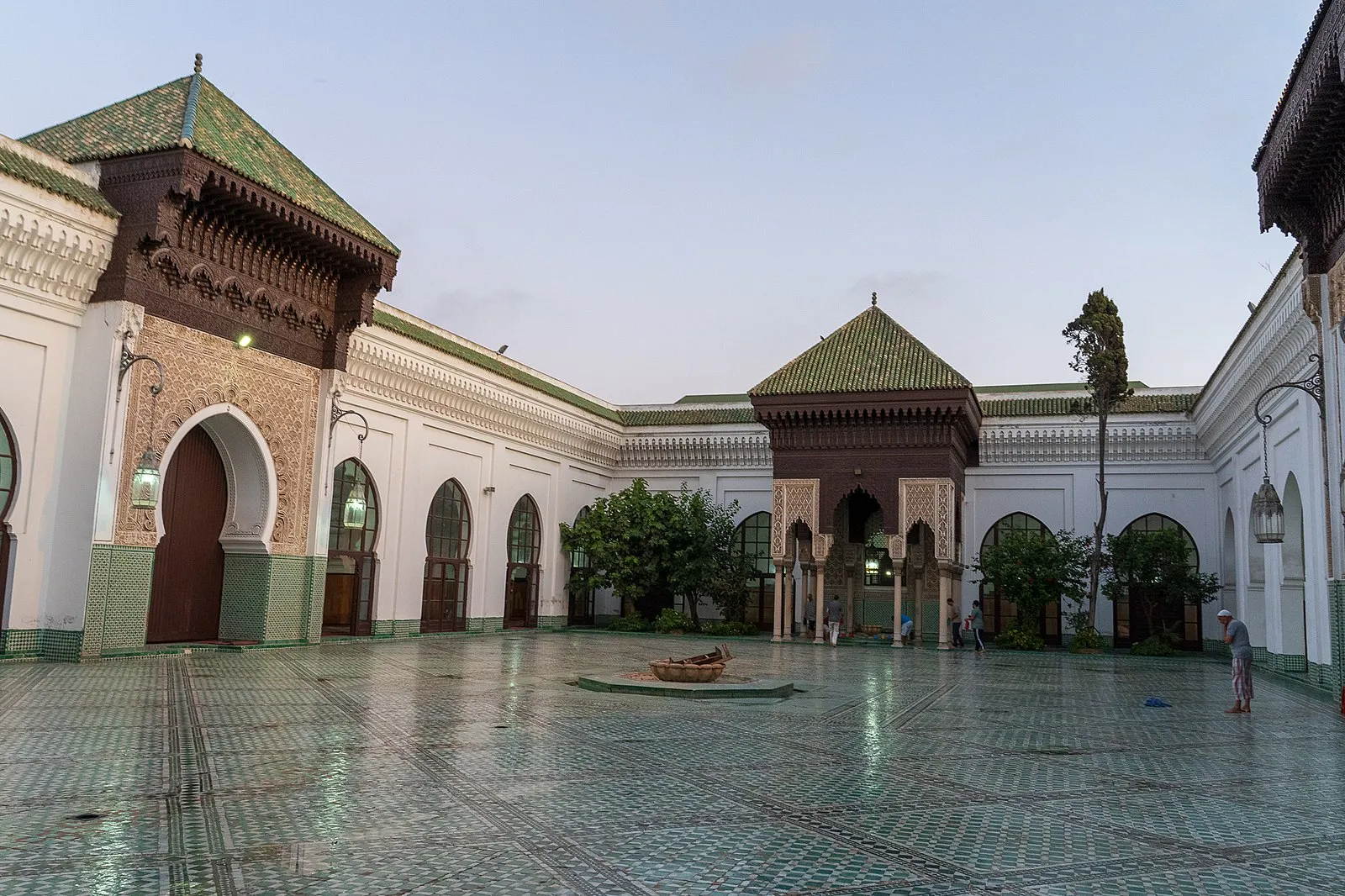 Moroccan mosque courtyard with green-tiled zellige and horseshoe arches