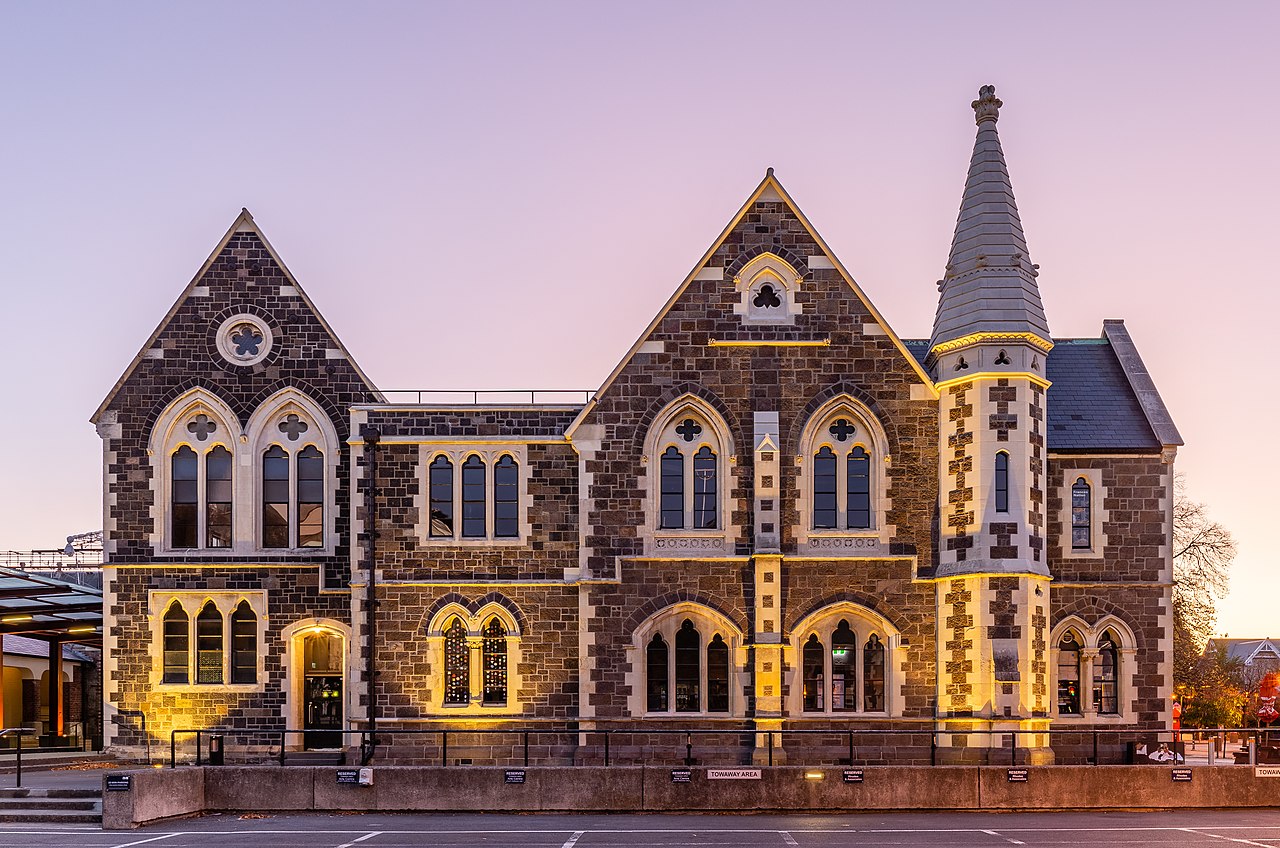 Canterbury Museum Gothic Revival stone facade illuminated at twilight with pointed arches and spire