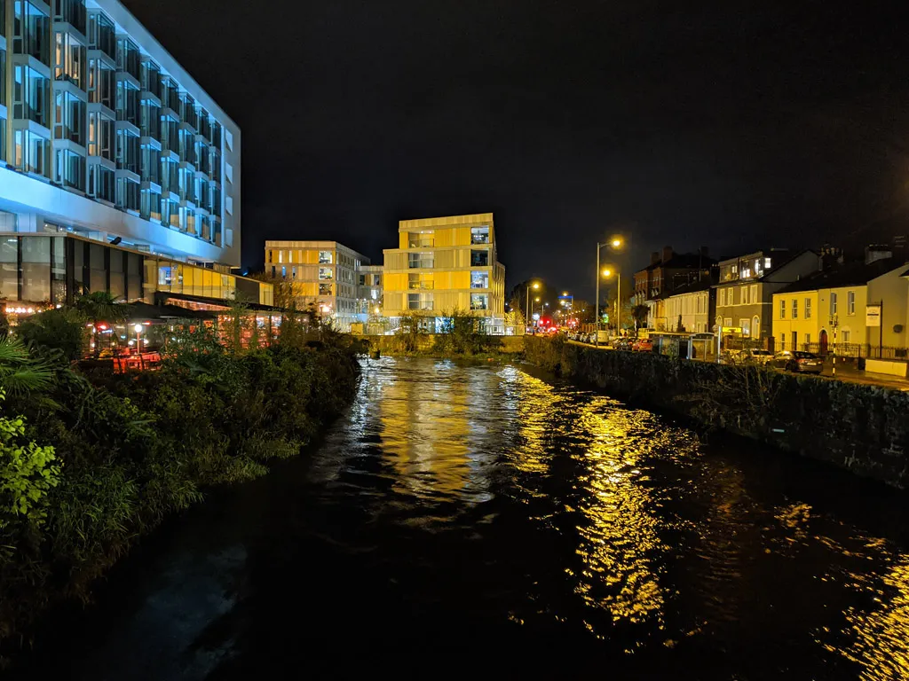 Cork city at night with the River Lee reflecting golden lights from buildings along the quay