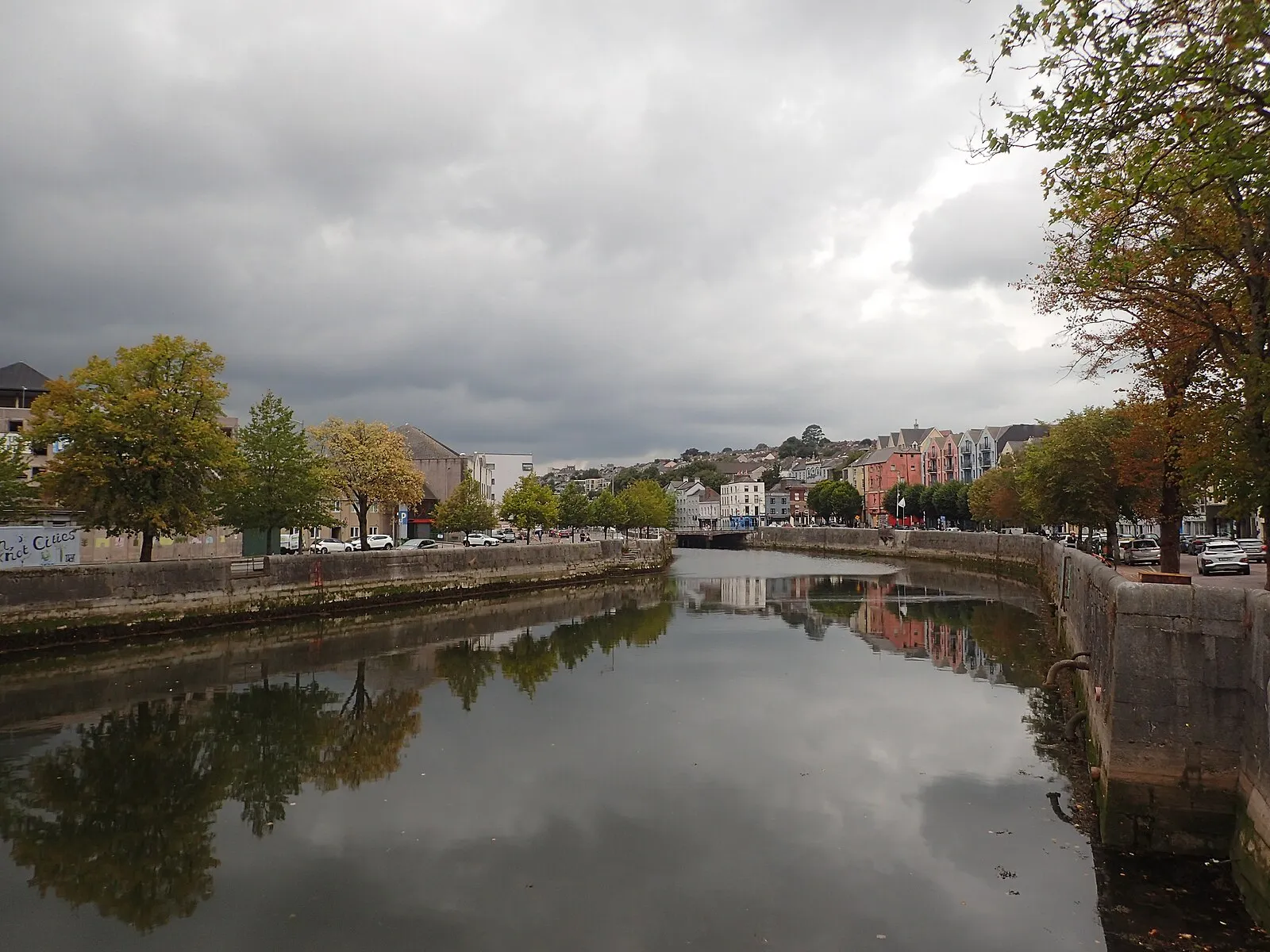 Autumn view along the River Lee in Cork with Georgian buildings reflected in still water under moody skies