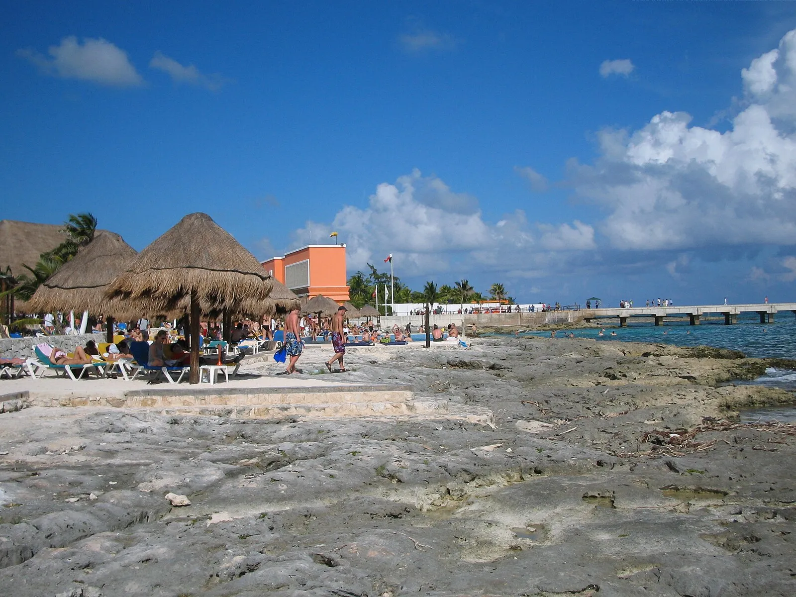 Costa Maya port beach area with palapa umbrellas and orange building