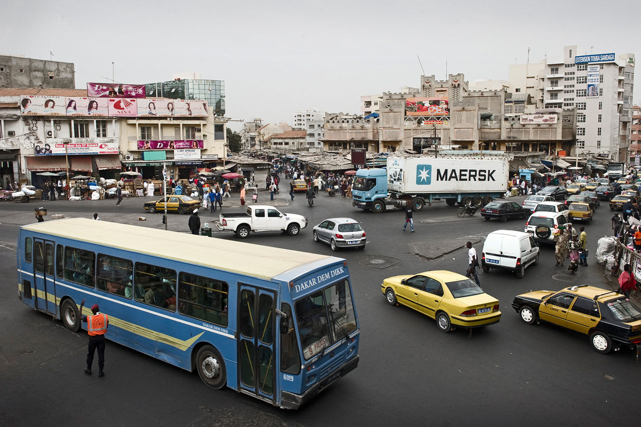 Busy Dakar intersection with Dakar Dem Dikk bus, Maersk truck, and yellow taxis