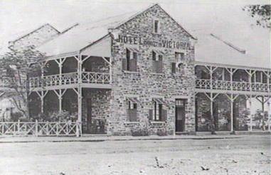 Historical black and white photograph of Hotel Victoria in early Darwin, a stone building with wraparound verandas