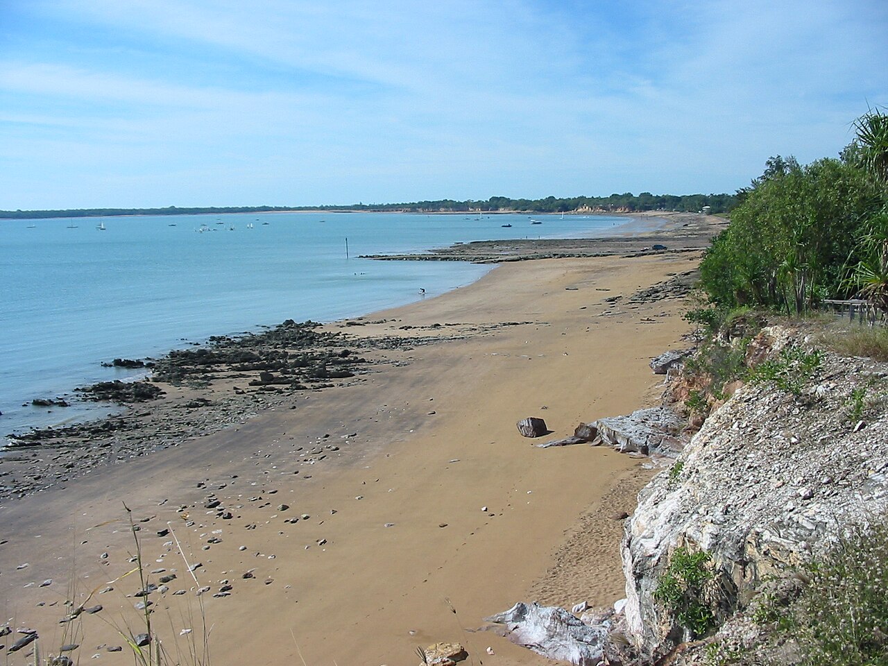 Sandy beach at low tide with boats anchored in calm turquoise water near Darwin