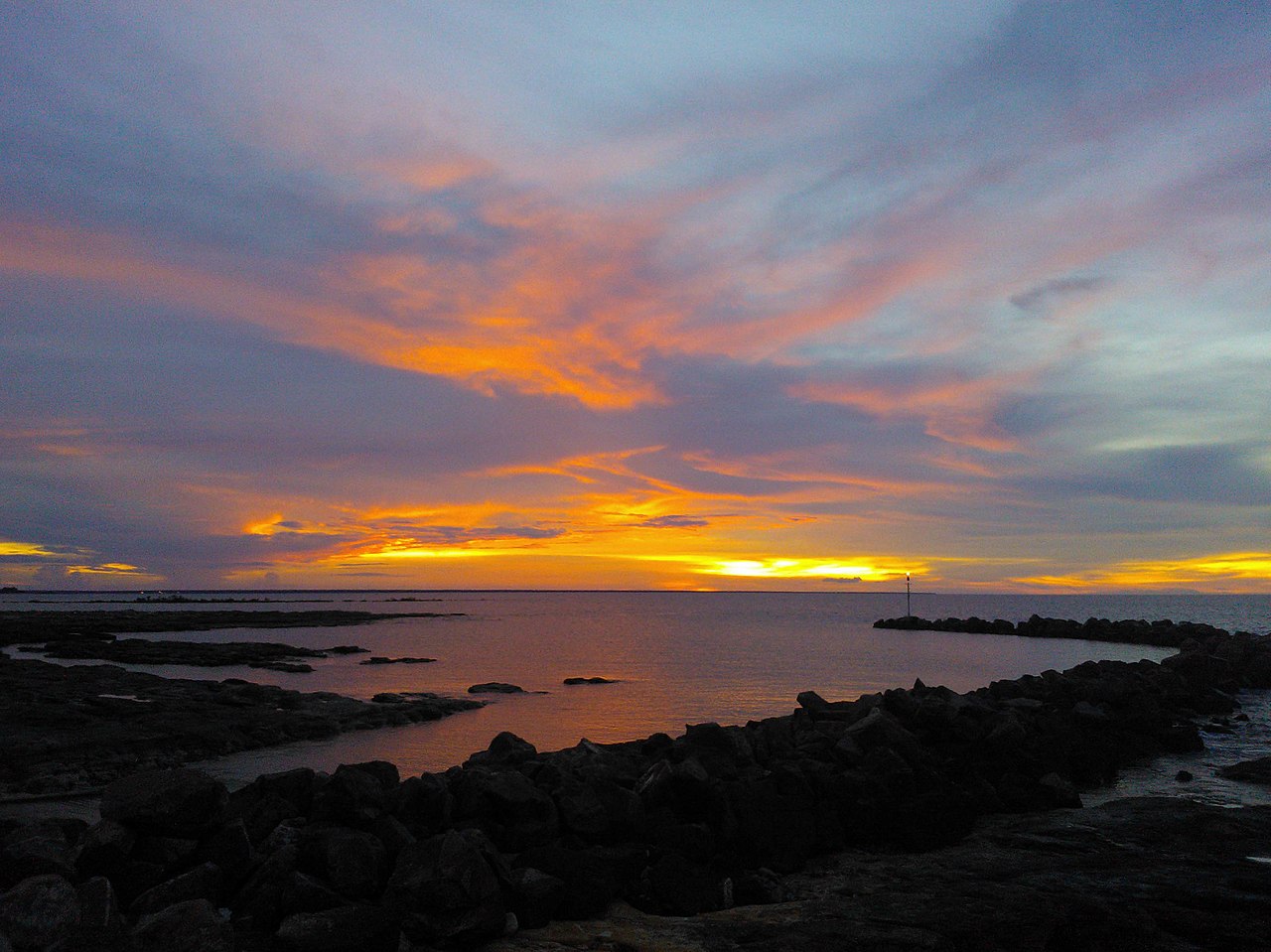 Dramatic orange and purple sunset over rocky coastline on the Timor Sea near Darwin