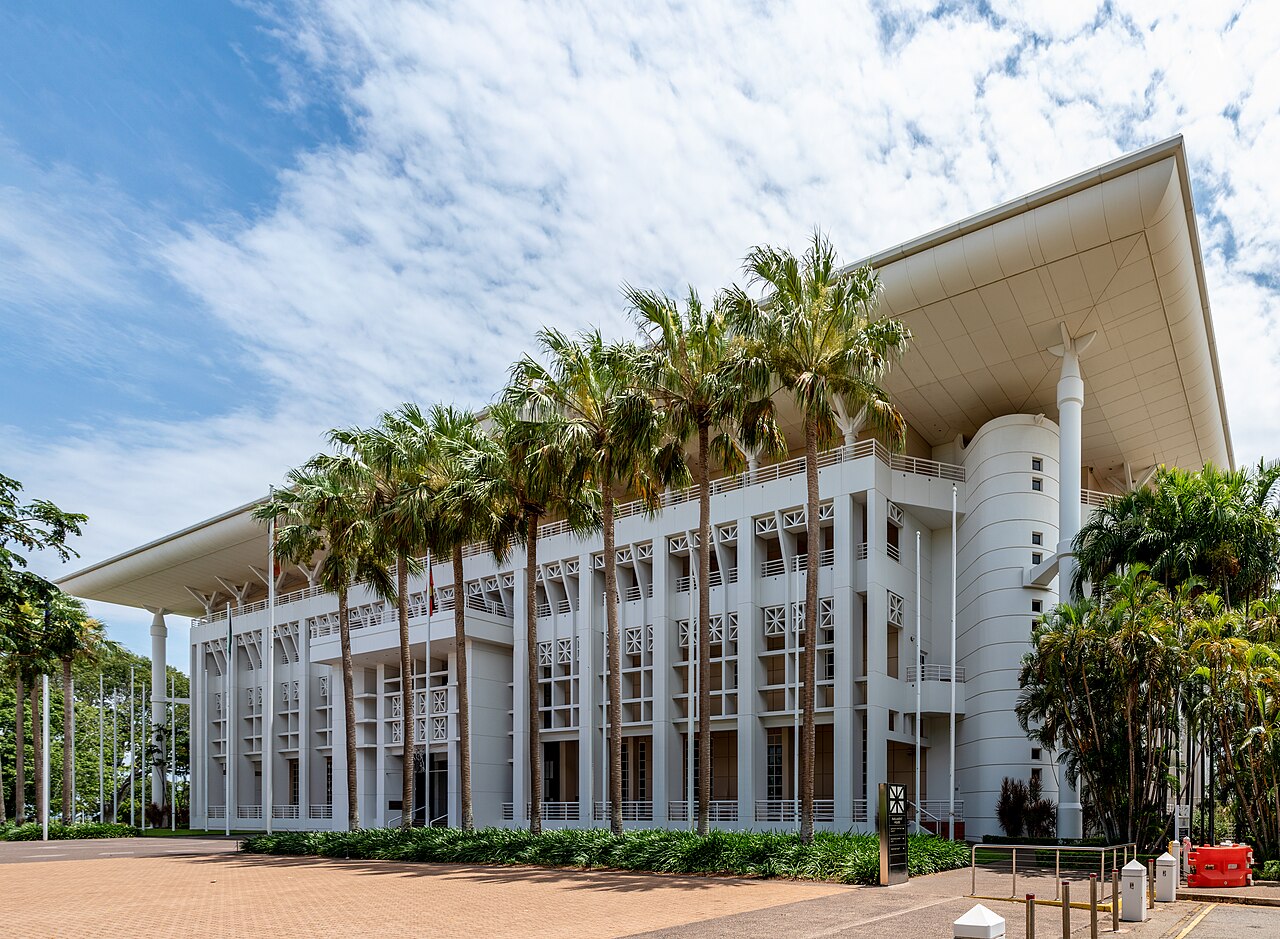 Northern Territory Parliament House in Darwin with palm trees and distinctive sloped roof