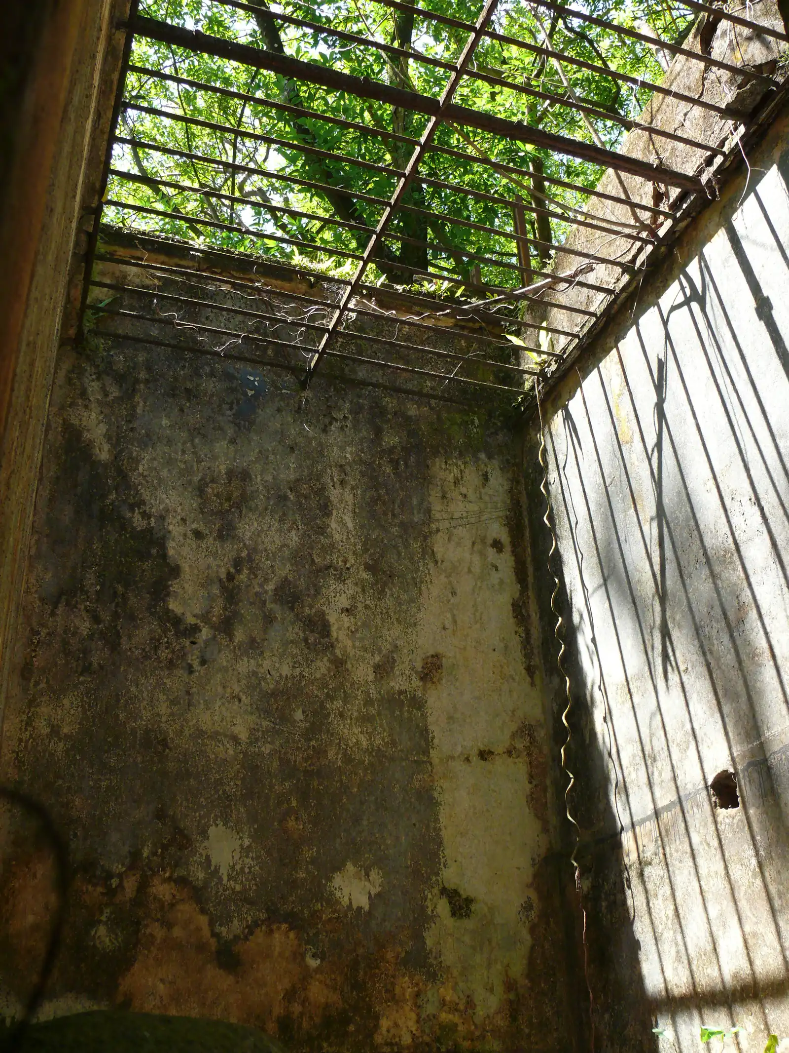 A single solitary-confinement cell on Île Saint-Joseph, its stone walls bare and its doorway open