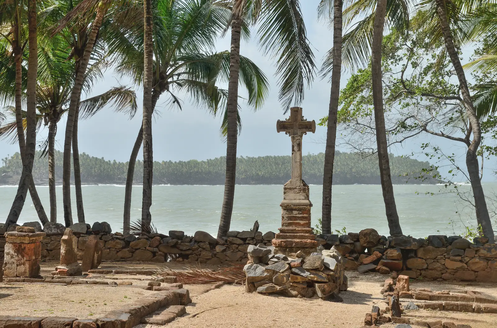 The warders' cemetery on Île Saint-Joseph, with a stone cross and grave slabs among palms