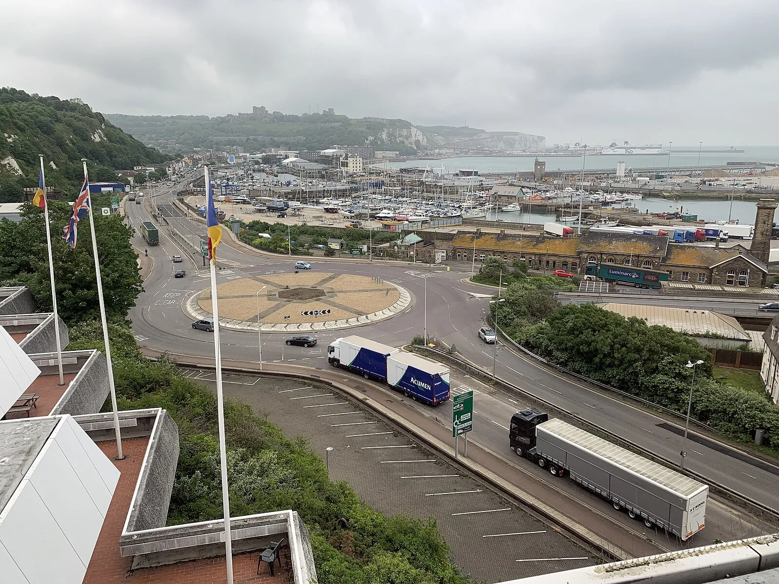 Elevated view of Dover harbor with roundabout, marina, white cliffs, and Dover Castle on the hill