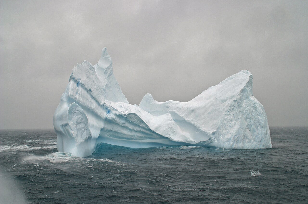 Massive iceberg sculpted by wind and waves in the rough grey waters of the Southern Ocean