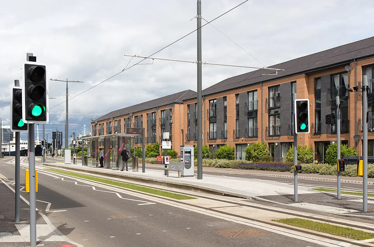 Edinburgh Trams stop near the cruise port with overhead wires and modern apartments, cruise ship visible in background