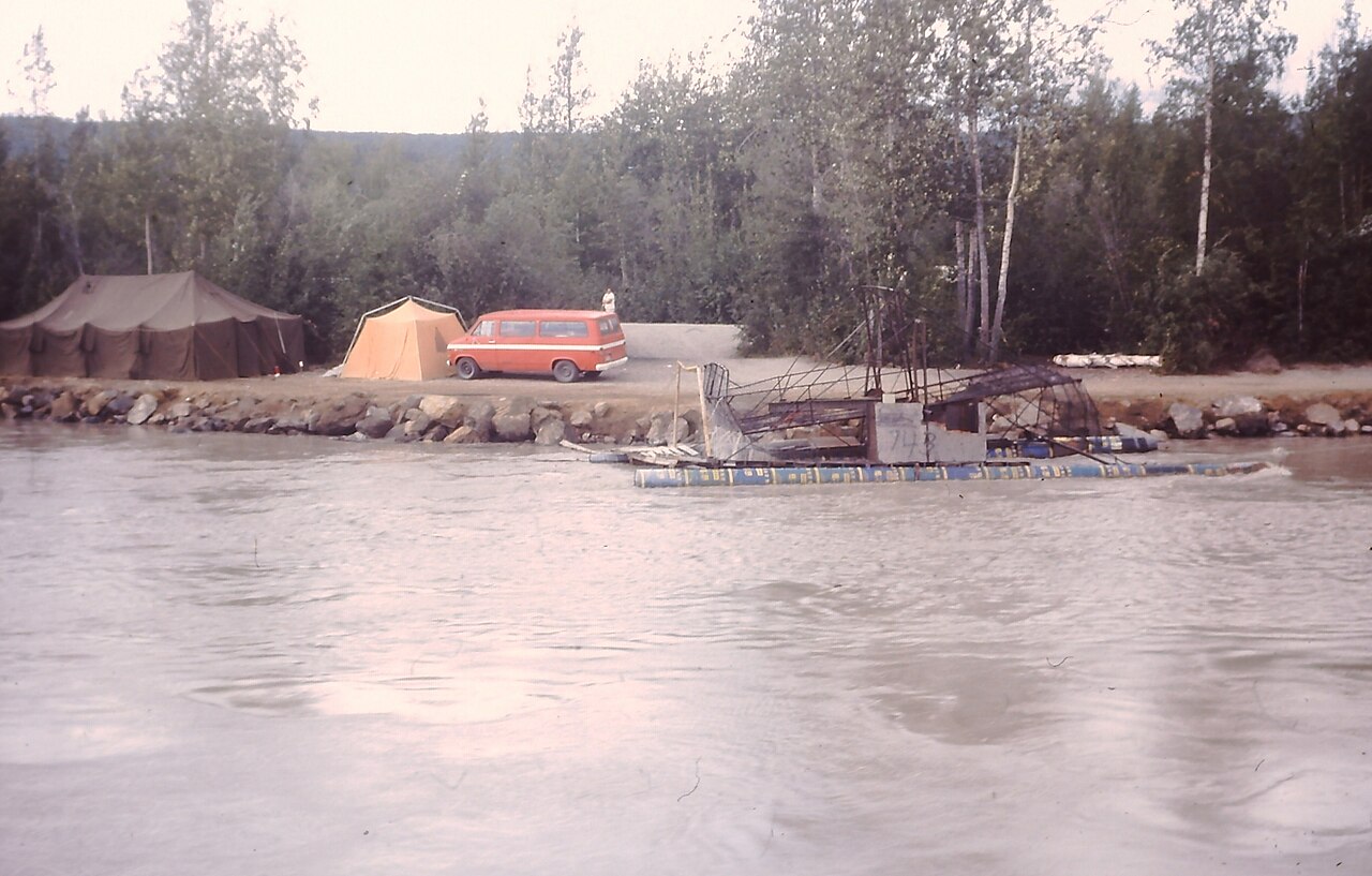 Fish wheel camp and tents along Alaskan river viewed from Discovery riverboat, 1976