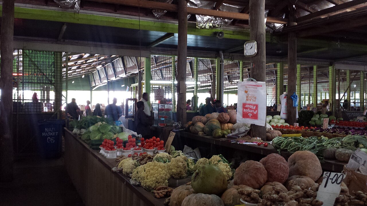 Interior of Nadi Municipal Market in Fiji with stalls of tropical produce including taro, breadfruit, and cauliflower