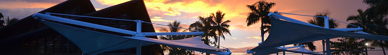 Tropical sunset with palm trees silhouetted and shade sails at a Fijian resort