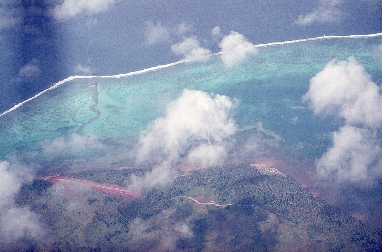 Pristine Fiji beach with palm trees, turquoise water, and traditional outrigger canoe