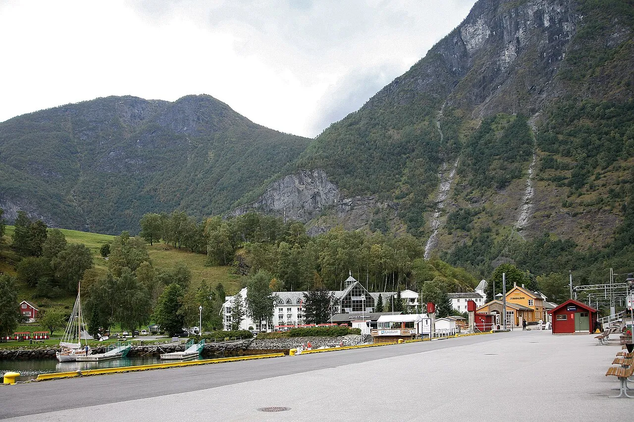Aurlandsfjord in Flam Norway with steep green mountains rising from mirror-still water and a small village nestled at the fjord head