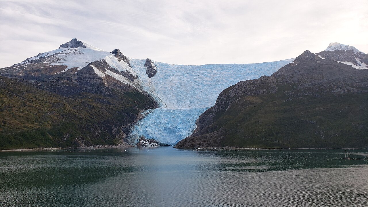 Tidewater glacier descending between mountains into a Patagonian fjord