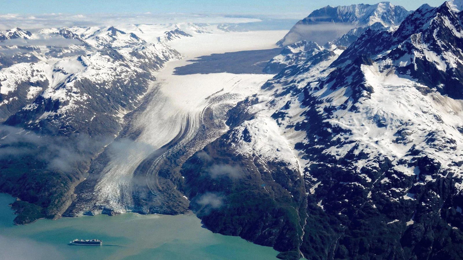 Aerial view of Lamplugh Glacier with a cruise ship dwarfed at its terminus