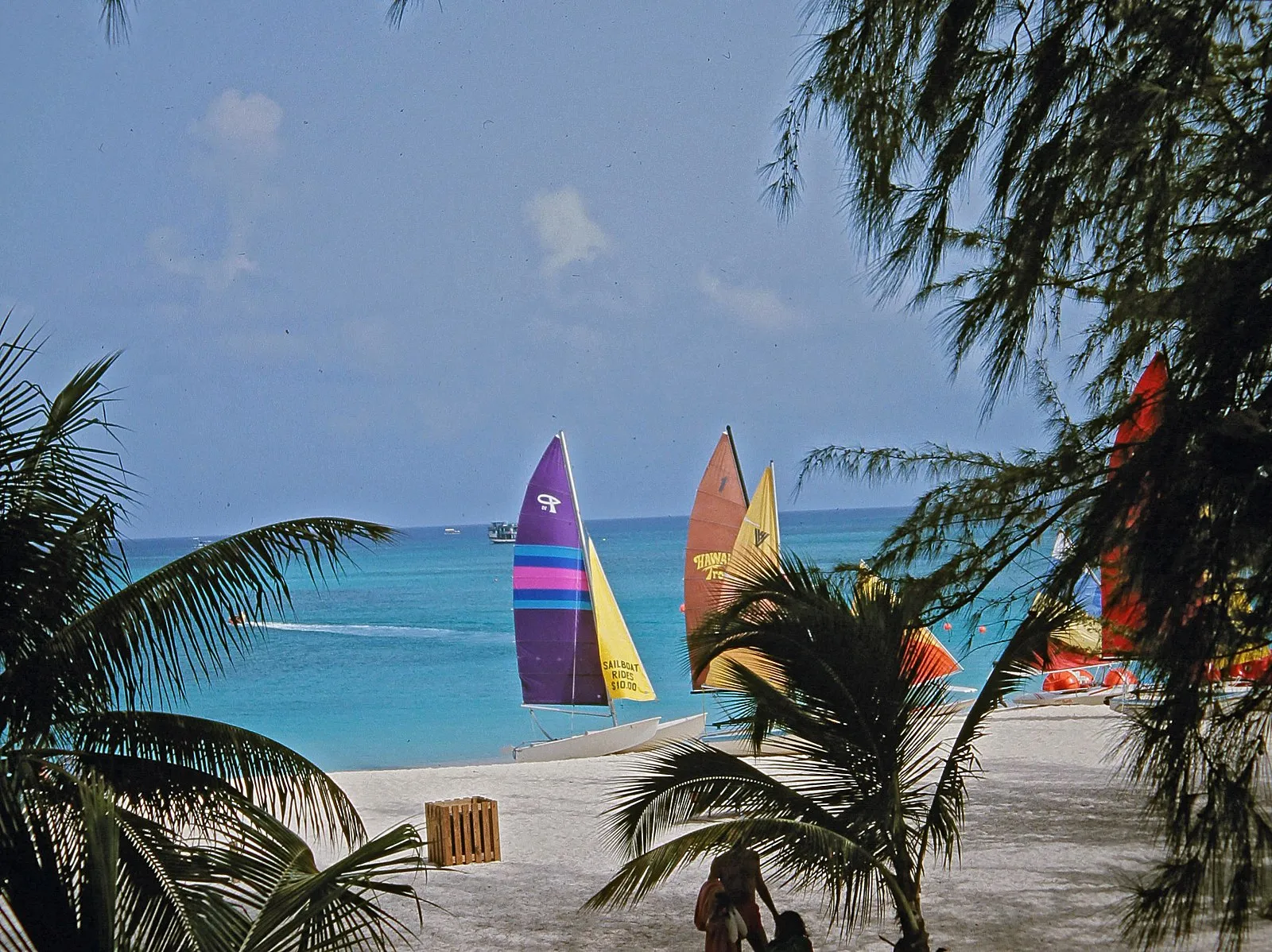 Colorful sailboats on white sand beach with turquoise Caribbean water