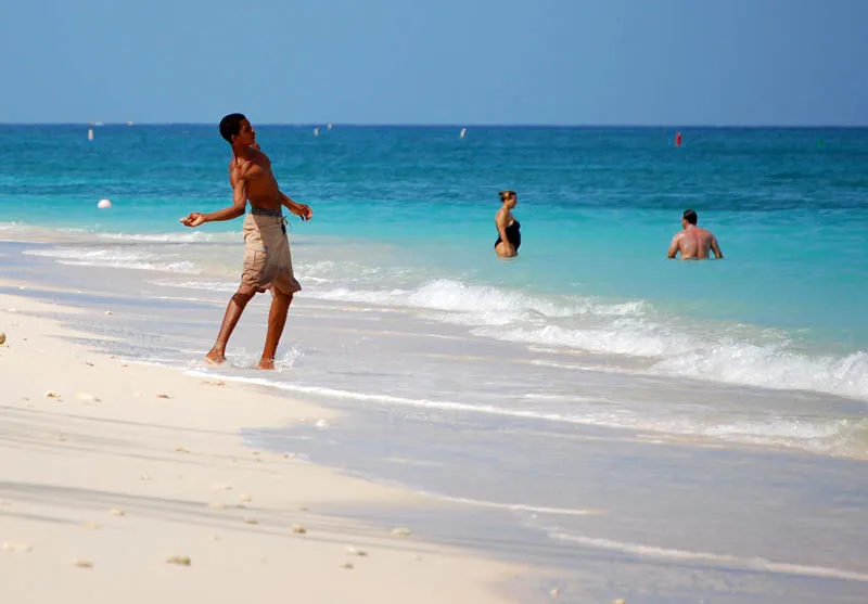 Beachgoers enjoying white sand and turquoise surf in Grand Cayman
