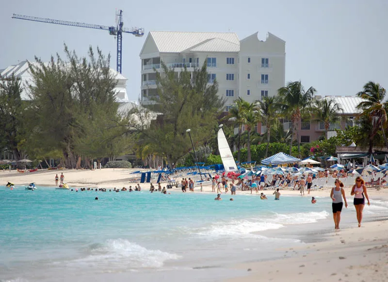Busy beach scene at Seven Mile Beach with hotels and swimmers