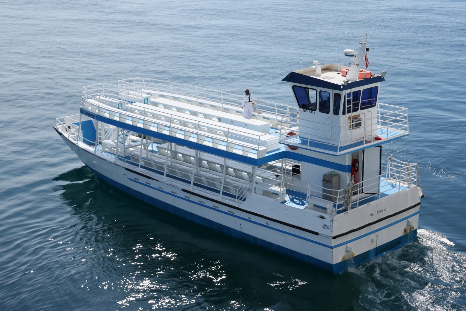 The double-deck tender boat named Great Stirrup Cay 1 crossing calm water with a crew member on the upper deck
